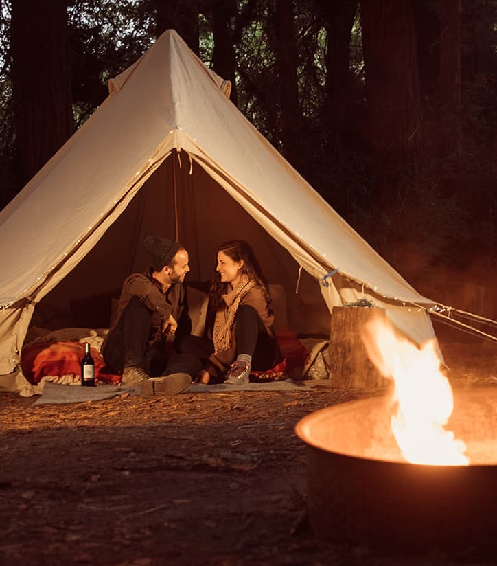 Couple glamping sitting in a tent with duraflame fire in foreground