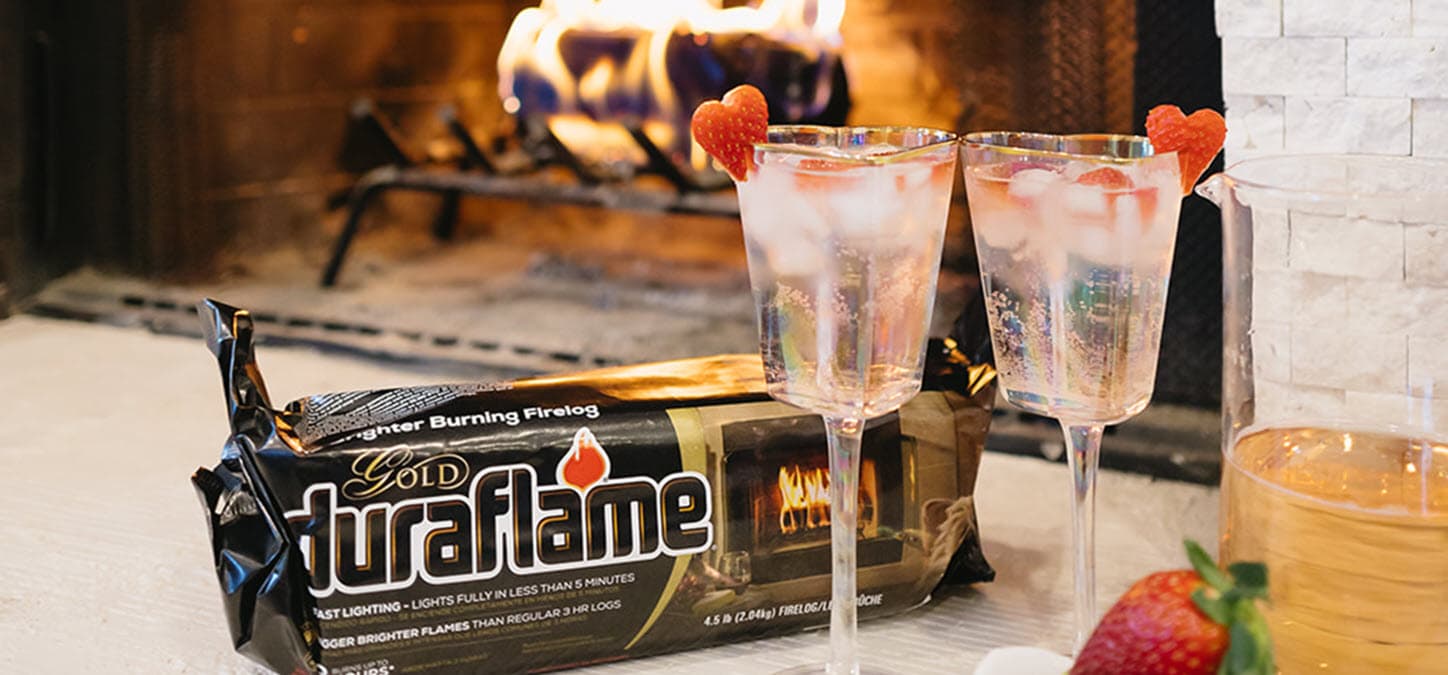 duraflame Gold firelog with cocktails and strawberries with burning firelog in background