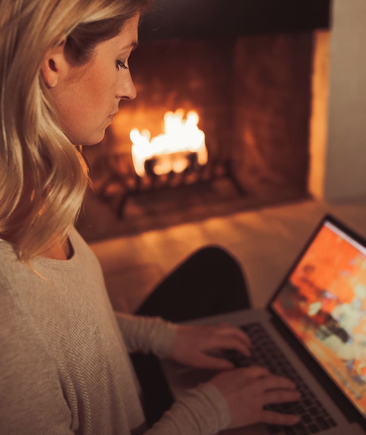 Woman with laptop near hearth burning a Duraflame firelog