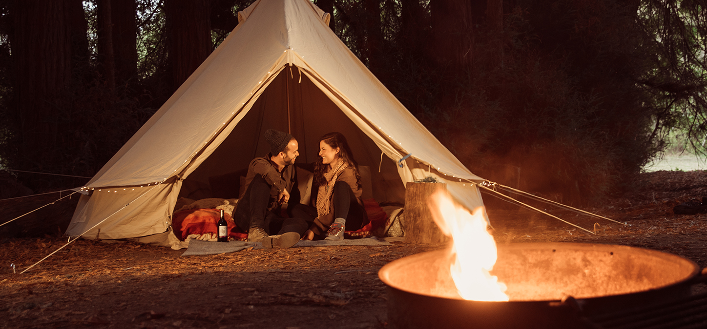 Couple glamping sitting in a tent with duraflame fire in foreground