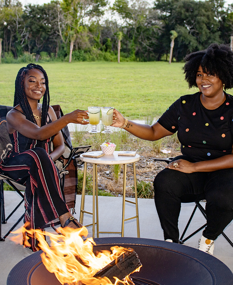 Ladies cheering with drinks while enjoying a duraflame fire in a fire pit backyard 