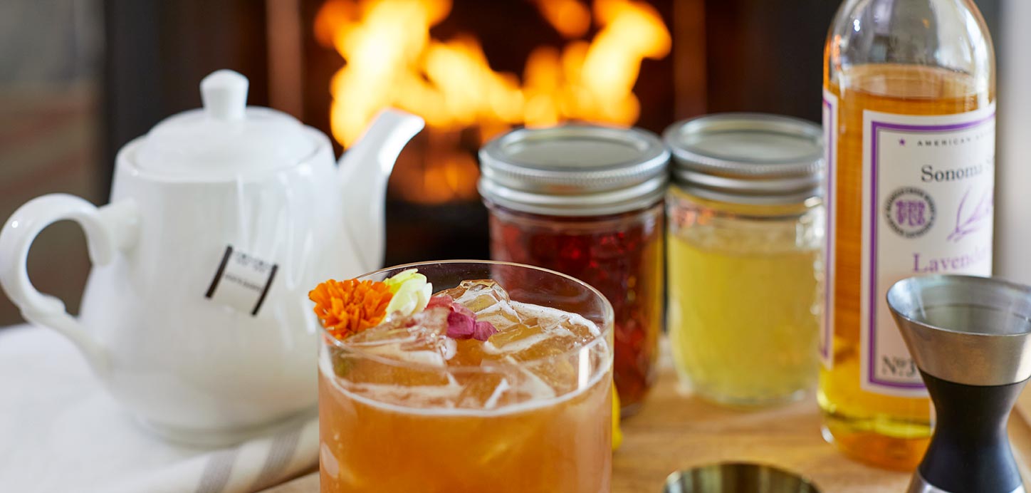 Ingredients for an Earl Grey cocktail with fire burning in hearth
