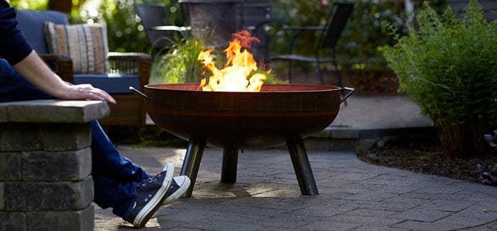 Person sitting next to duraflame OUTDOOR firelogs burning in a Backyard firepit