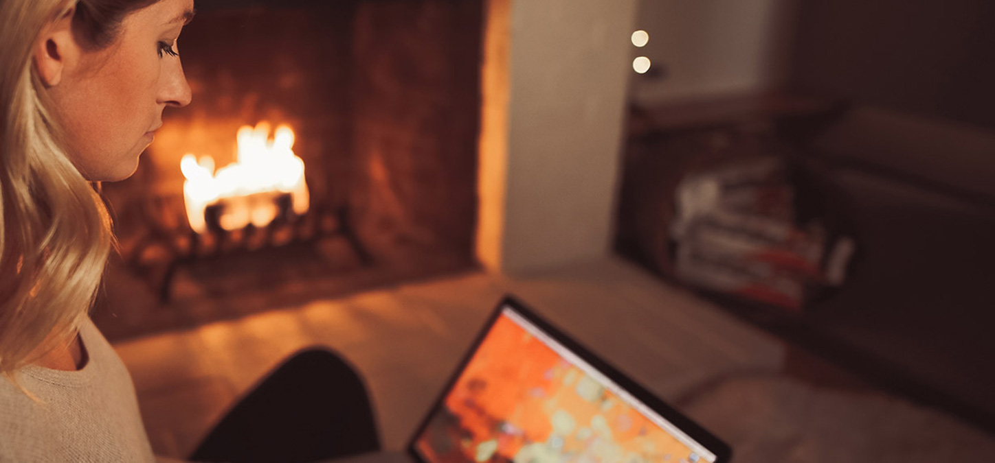Woman using laptop while enjoying a fire