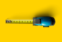 A birds eye view of a tape measurer on a bright yellow background