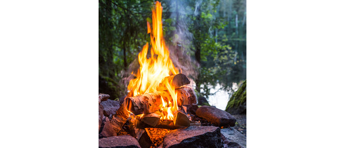 Roaring wood fire ignited with duraflame firestart firelighters in a rock campfire pit in the woods