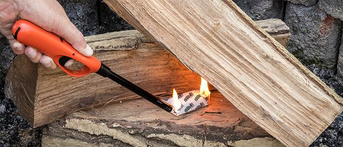 Lighter lighting a FIRESTART® CUBE FIRESTARTER to ignite wood in a fireplace