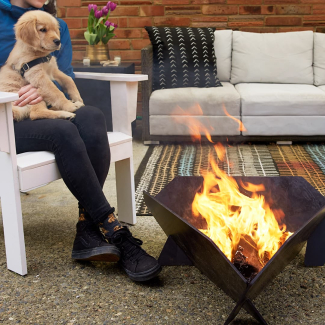Duraflame OUTDOOR firelogs burning in outdoor firepit with person and dog sitting next to fire