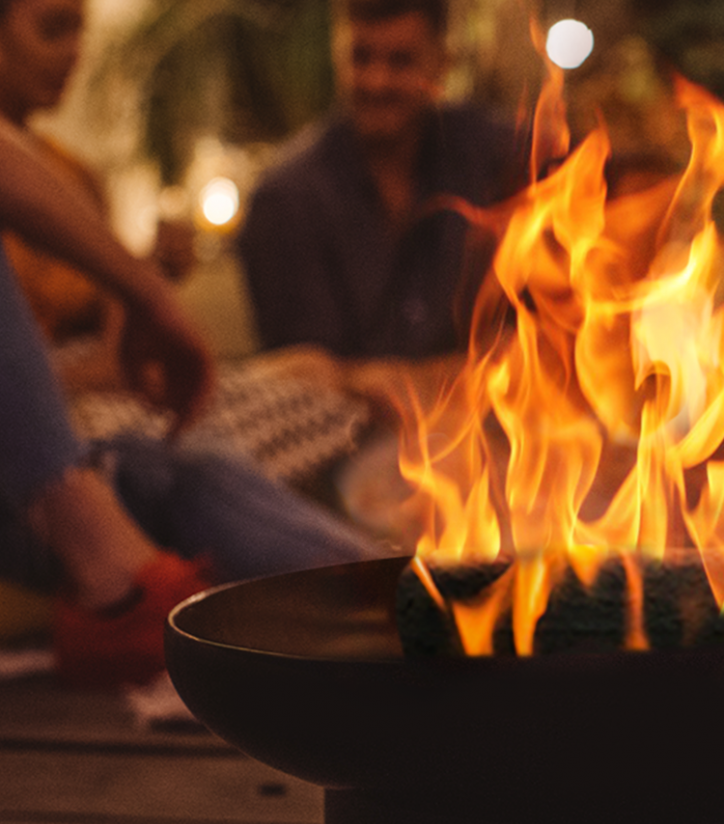 close up of a Duraflame firelog burning in fire pit with friends gathered around in background