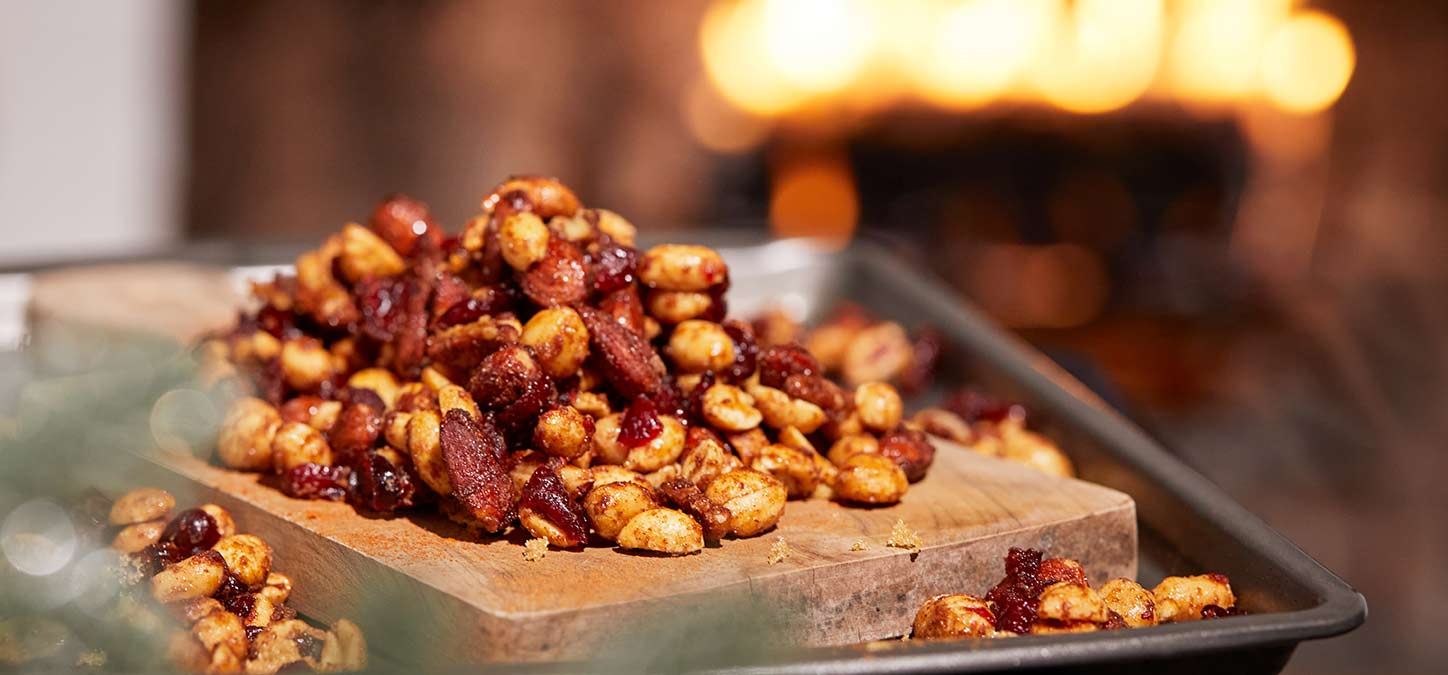 Pile of spiced mixed nut snack with a Duraflame firelog buring in the background