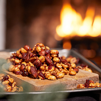 Pile of spiced mixed nut snack with a Duraflame firelog buring in the background