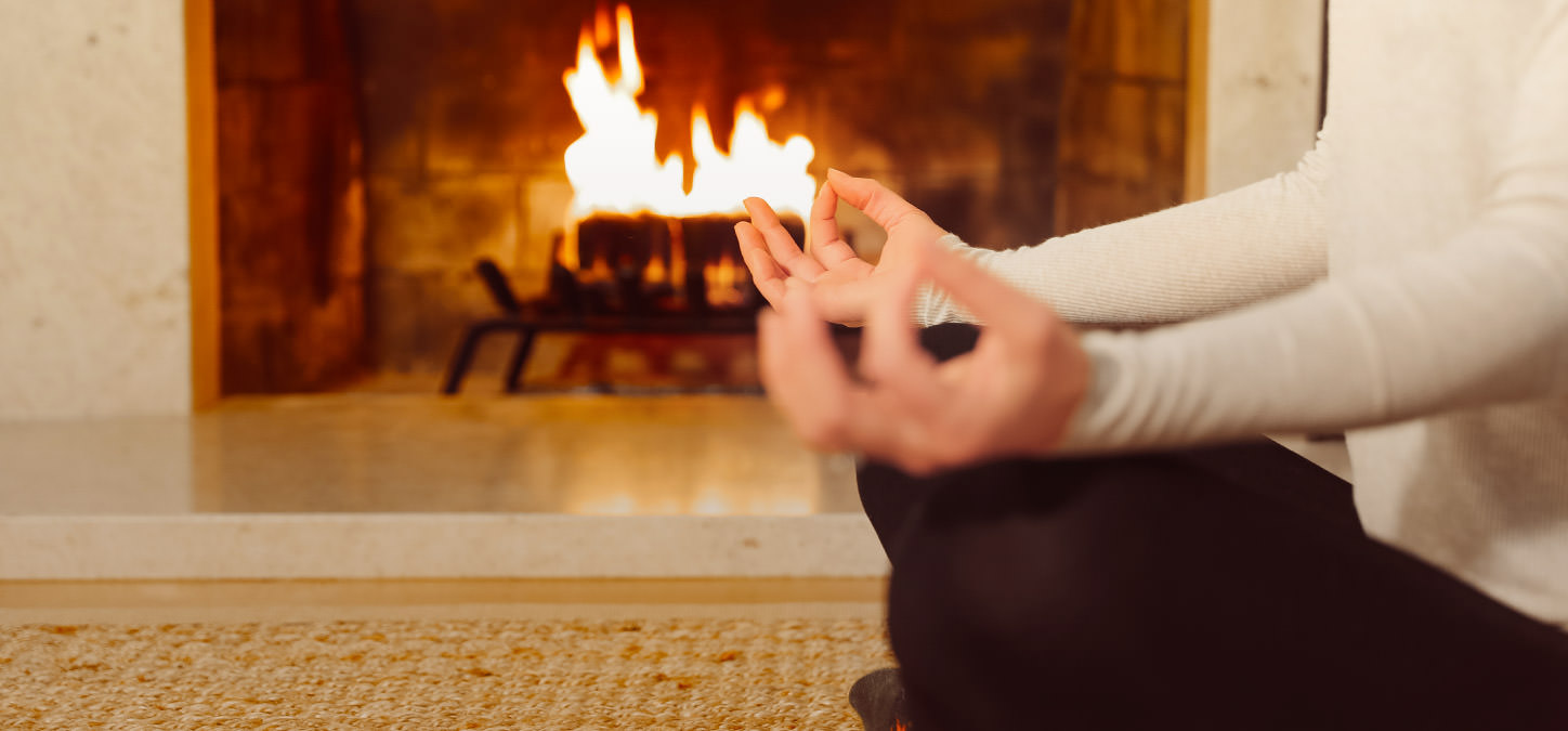 Hands in Yoga pose with duraflame fire burning in background