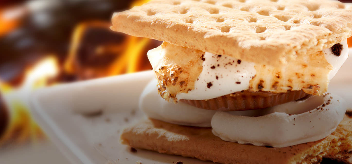 Roasted marshmallow, peanut butter cup & white chocolate covered pretzels s'mores with flames in background