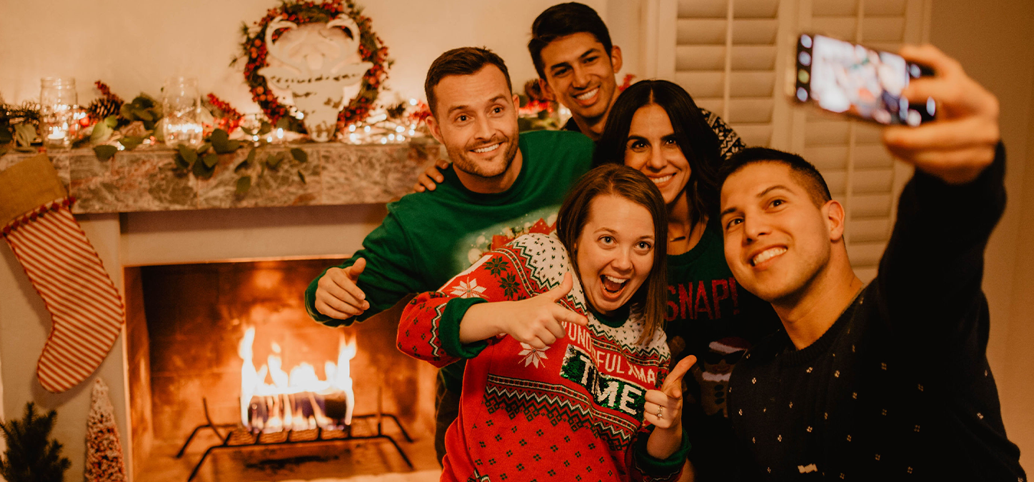 Group of friends wearing ugly sweaters by the fire taking a selfie