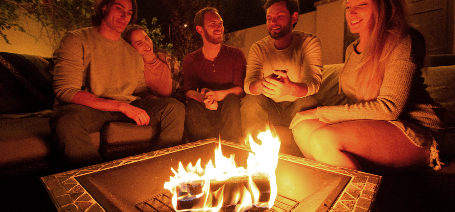Group of friends enjoying a duraflame firelog in the backyard fire pit at night