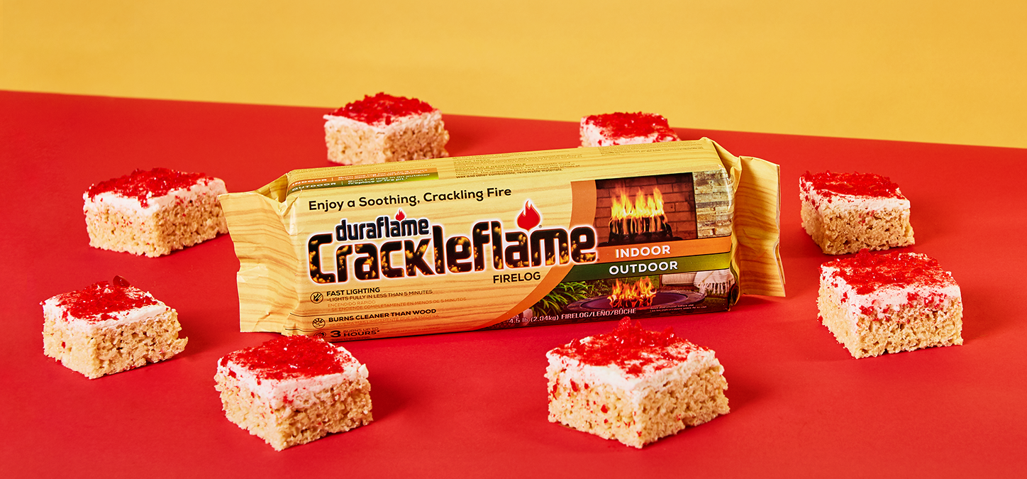 A Crackleflame firelog in its packaging surrounded by Hot Cinnamon Rice Cereal Treats 