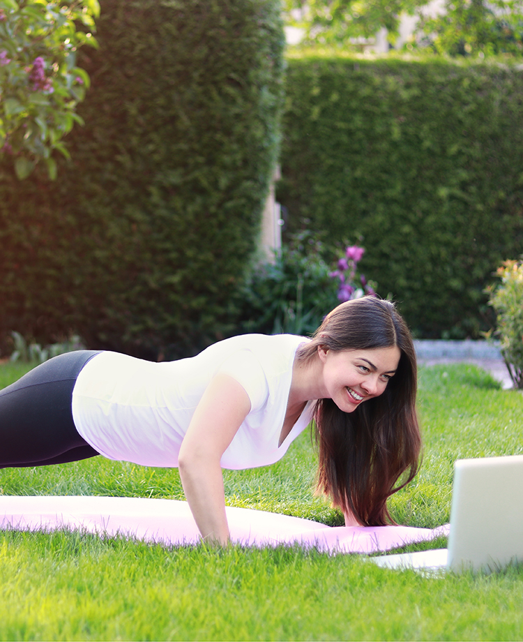 Woman in fitness clothing doing a plank in backyard