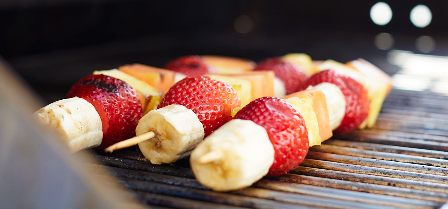 Fruit Skewers with bananas, strawberries, pineapple and melon on a grill