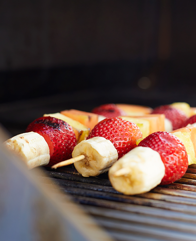 Fruit Skewers with bananas, strawberries, pineapple and melon on a grill