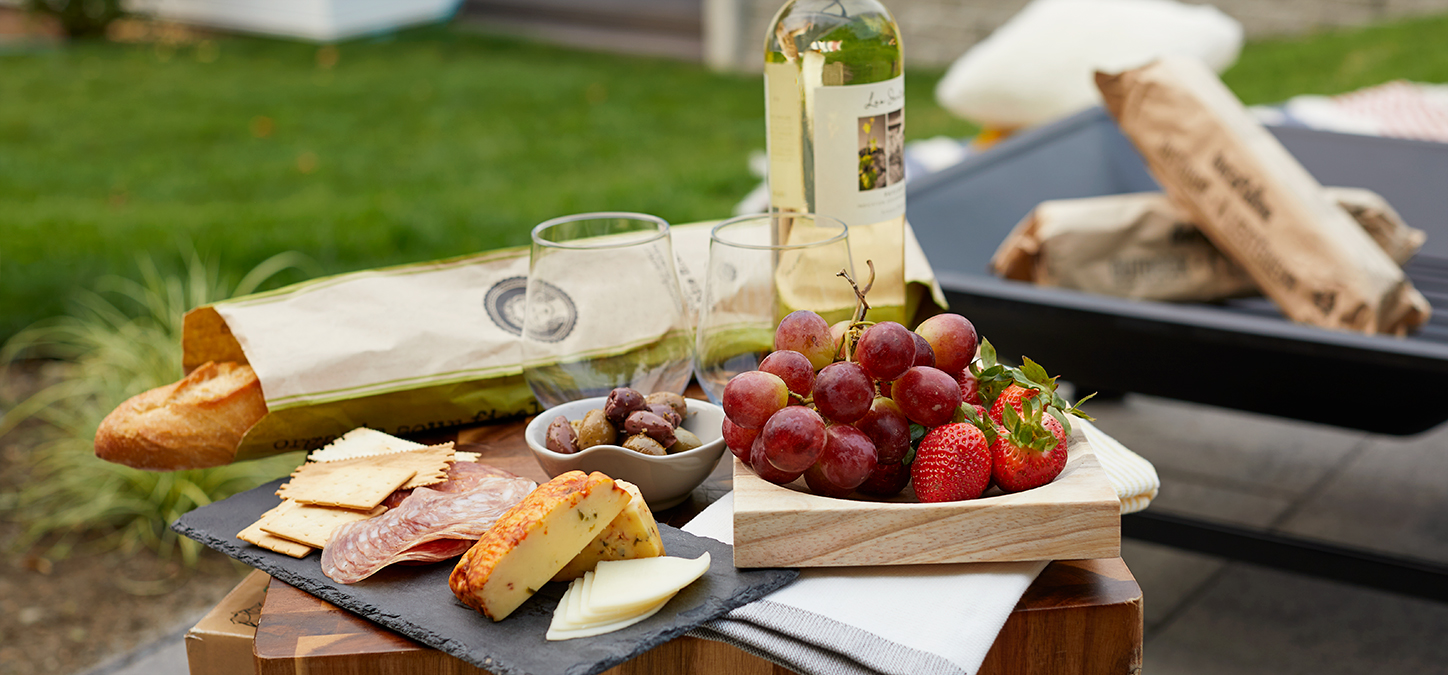 Picnic foods and wine in the backyard with duraflame OUTDOOR firelogs in the fire pit in background