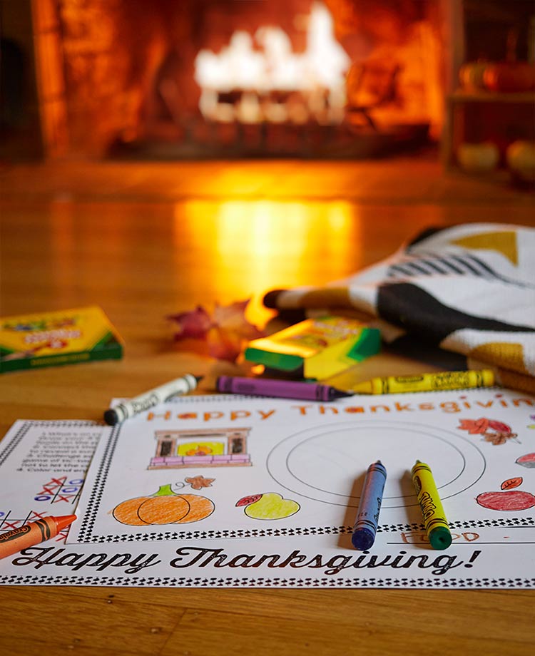 Thanksgiving themed placemats and crayons with duraflame fire burning in the background