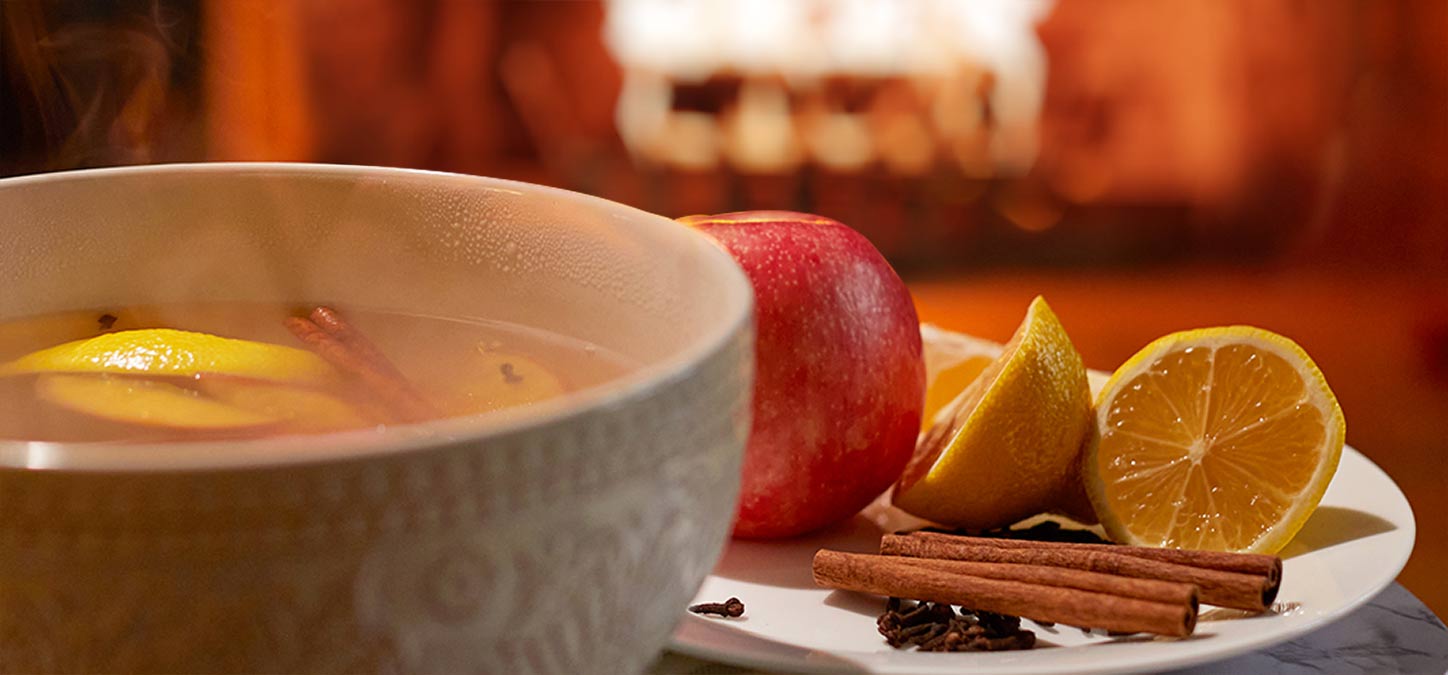 Potpourri in a bowl with apple, lemon and spices and duraflame fire burning in background