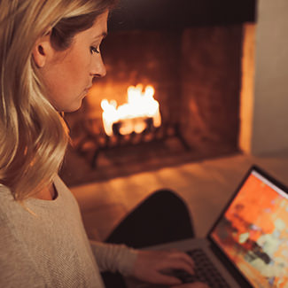 Woman with laptop near hearth burning a Duraflame firelog