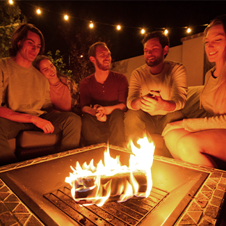Group of friends enjoying a duraflame firelog in the backyard fire pit at night