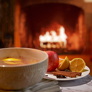 Potpourri in a bowl with apple, lemon and spices and duraflame fire burning in background