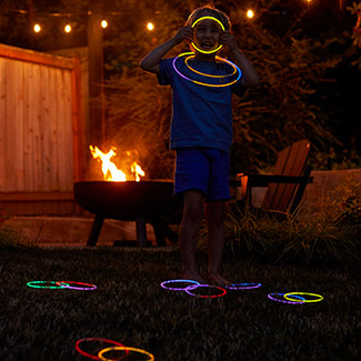 Kid playing glow ring toss by the camp fire
