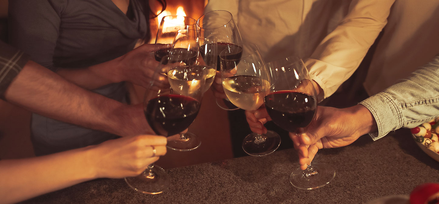 Close up of 6 wine glasses in a toast with fire in background