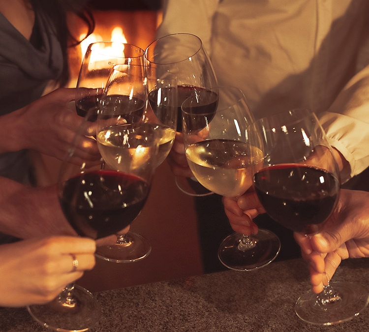 Close up of 6 wine glasses in a toast with fire in background