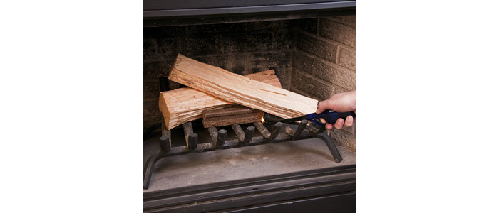 Lighter lighting a QUICK START® FIRELIGHTER to start a wood fire in an indoor fireplace