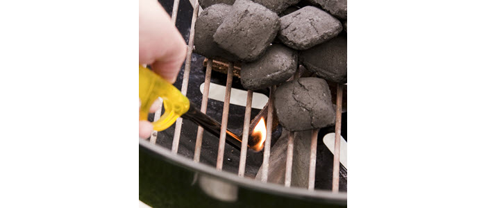 Lighter lighting STIX® FIRELIGHTERs to start a charcoal fire in a BBQ