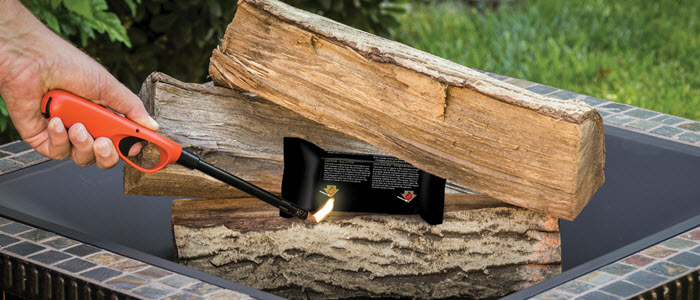 Lighter lighting a FIRESTART® GOLD FIRELIGHTER to start a wood fire in outdoor fire pit
