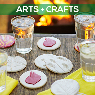 Clay coaster and drinks on a table next to an outdoor fireplace